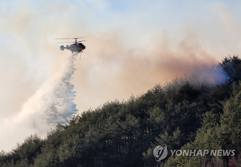 A firefighting helicopter dumps water on a hill in the eastern city of Samcheok, Gangwon Province, on March 5, 2022, to put out a wildfire that has ravaged the area since the previous day. (Yonhap)
