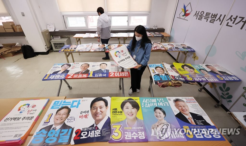 Los funcionarios electorales chequean los pósteres de los candidatos a las elecciones locales del 1 de junio, el 18 de mayo de 2022, en la oficina de un comité de administración electoral, en Seúl.