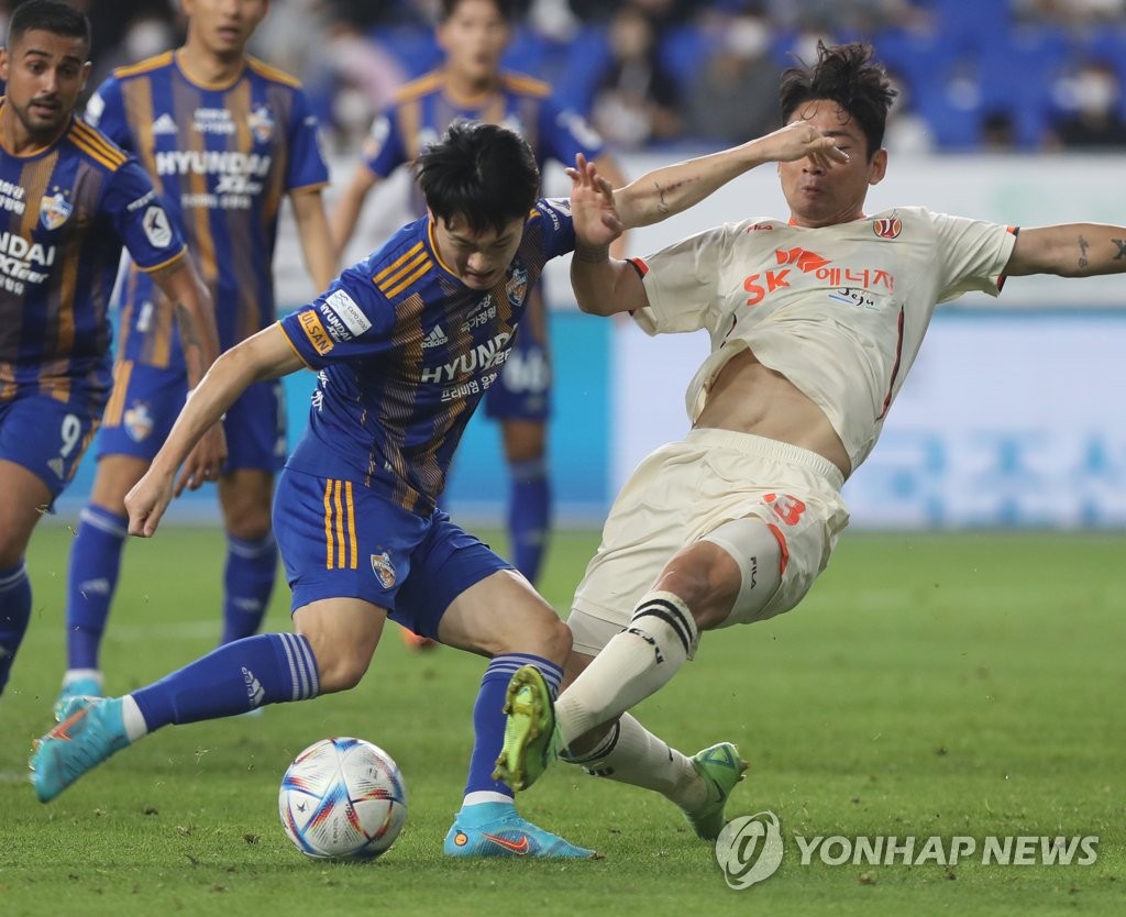 Um Won-sang of Ulsan Hyundai FC (L) attempts a shot past Chung Woon of Jeju United during the clubs' K League 1 match at Munsu Football Stadium in Ulsan, 415 kilometers southeast of Seoul, on May 18, 2022. (Yonhap)