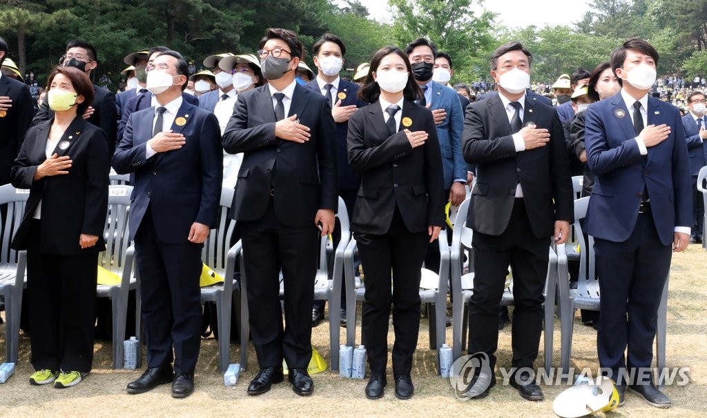 Leaders of the ruling People Power Party (PPP) and the main opposition Democratic Party (DP) salute to the national flag during a memorial service for the late President Roh Moo-hyun in Bongha Village, Gimhae, some 450 kilometers southeast of Seoul, on May 23, 2022. (Pool photo) (Yonhap)
