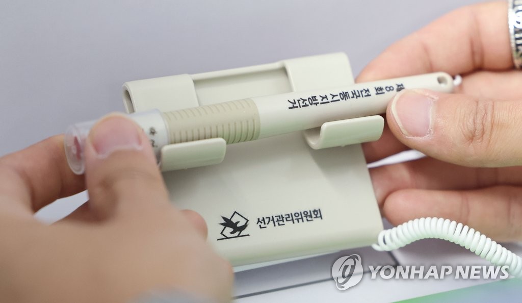 An election official checks a ballot marking device at a polling station in Seoul on May 25, 2022. (Yonhap)