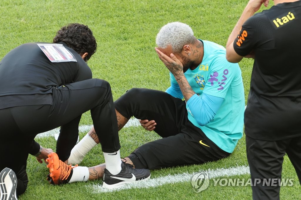 Brazilian forward Neymar (R) is attended to by a team trainer after sustaining an apparent right foot injury during a training session at Seoul World Cup Stadium in Seoul on June 1, 2022, the eve of a friendly match against South Korea. (Yonhap)