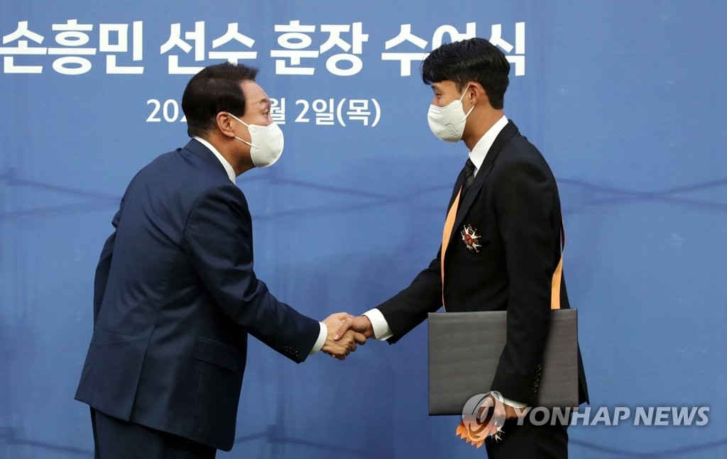 President Yoon Suk-yeol (L) shakes hands with Son Heung-min, captain of the South Korean men's national football team, after awarding Son with the Cheongnyong Medal, the highest order of merit given to an individual for achievement in sports, prior to South Korea's friendly match against Brazil at Seoul World Cup Stadium in Seoul on June 2, 2022. (Yonhap)
