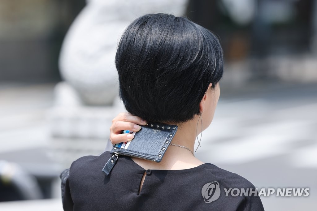 서울 종로구 청계천 인근에서 한 시민이 카드지갑으로 목 뒤에 내리쬐는 햇빛을 가리고 있다. [연합뉴스 자료사진]
