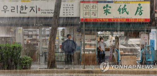 지난 11일 서울 종로구의 한 인도에서 시민들이 상점 처마에서 비를 피하고 있다. [연합뉴스 자료사진]
