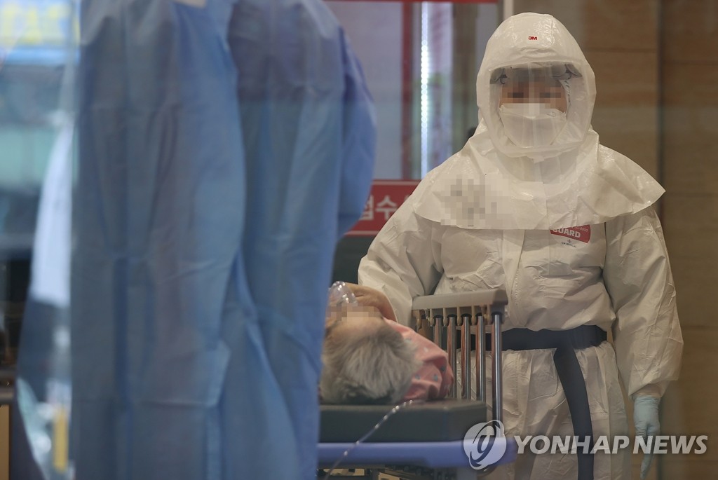 A medical worker stands beside an elderly patient being transported on a stretcher into a hospital in eastern Seoul on July 25, 2022. (Yonhap) 