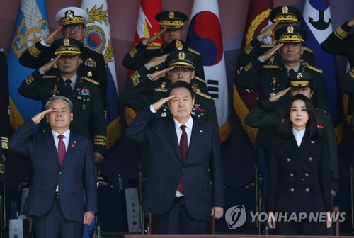 President Yoon Suk-yeol (C) salutes the national flag at an Armed Forces Day event at the Gyeryongdae military headquarters 160 kilometers south of Seoul on Oct. 1, 2022, flanked by Defense Minister Lee Jong-sup (L) and first lady Kim Keon-hee. (Yonhap)