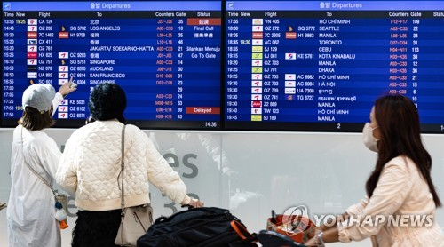 韓国の仁川国際空港でフライト情報を確認する旅行客＝１０日、仁川（聯合ニュース）