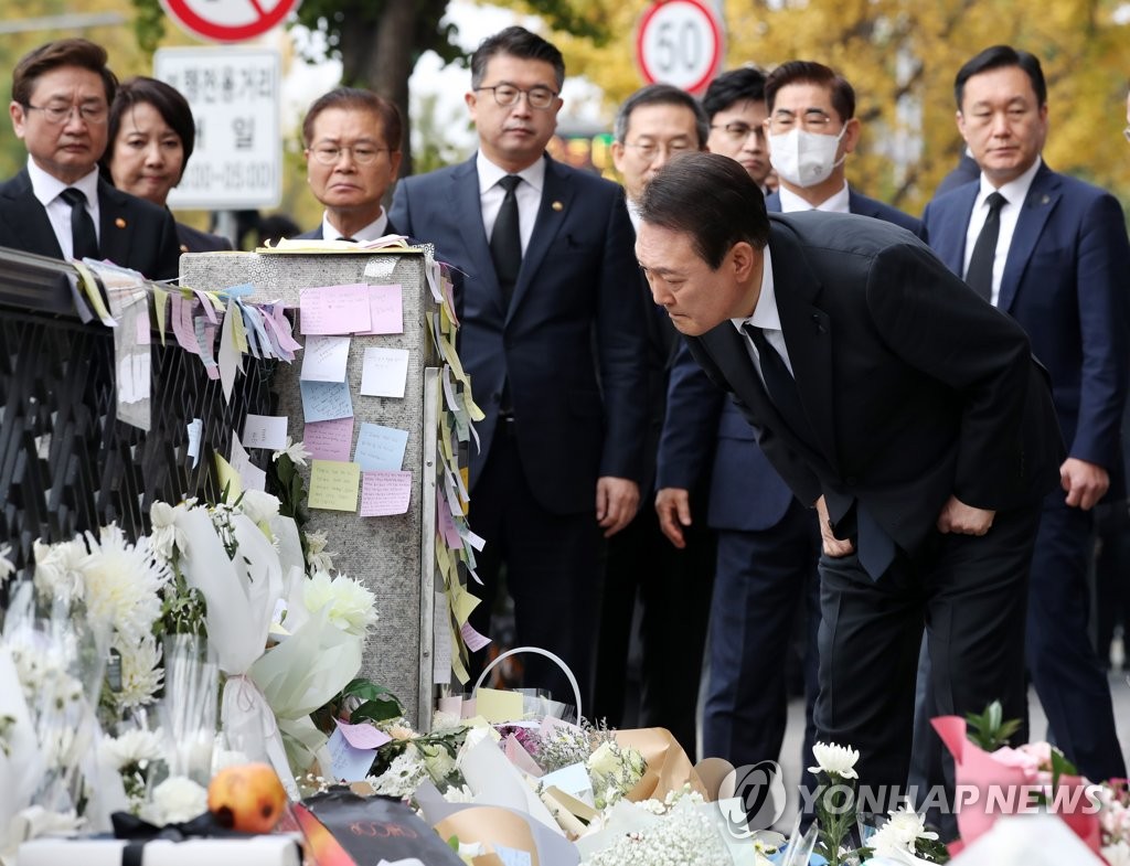 President Yoon Suk-yeol (R) reads memorial messages during a visit to a temporary mourning space near a downhill alley in Seoul's Itaewon district on Nov. 1, 2022, the site of a crowd crush on Oct. 29 that left 158 people, mostly in their 20s, dead during Halloween festivities. (Pool photo) (Yonhap)