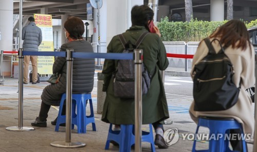 Des personnes attendent de recevoir un test Covid-19 devant un centre de dépistage situé dans le quartier de Mapo à Séoul, le 23 novembre 2022.