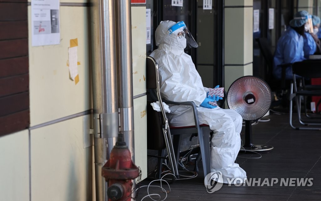 ソウル市内の新型コロナウイルス検査所で医療従事者がカイロを手に暖を取っている＝（聯合ニュース）