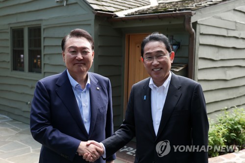 South Korean President Yoon Suk Yeol (L) shakes hands with Japanese Prime Minister Fumio Kishida during their summit talks at the Camp David presidential retreat in Maryland on Aug. 18, 2023. (Pool photo) (Yonhap)