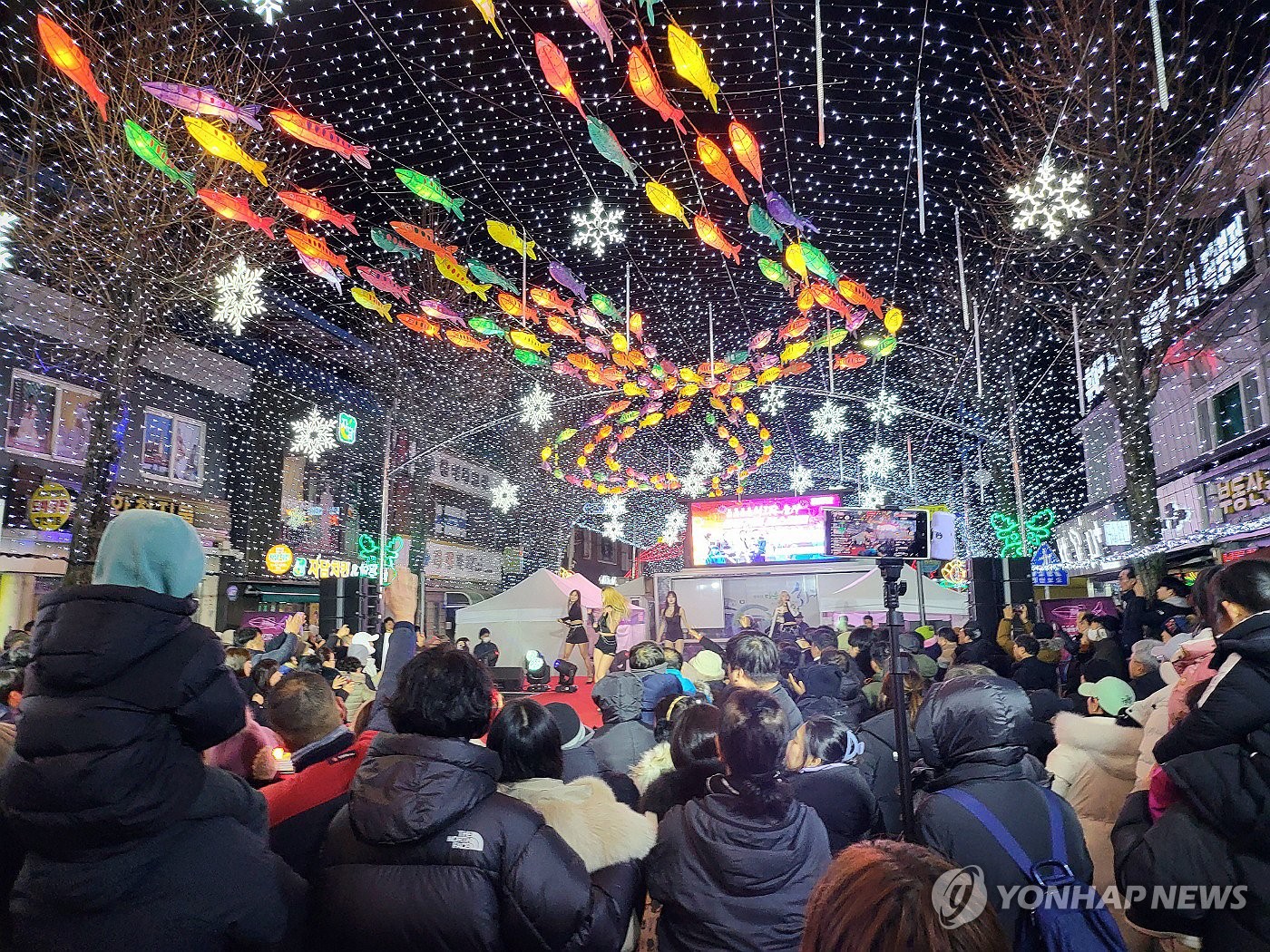 Los visitantes disfrutan de las luces de los barcos decoradas a lo largo de una calle en Hwacheon, en la provincia de Gangwon, a unos 90 kilómetros al noreste de Seúl, en celebración de la inauguración del Festival de Hielo Anual Sancheoneo de Hwacheon, el 6 de enero de 2024. (Yonhap)