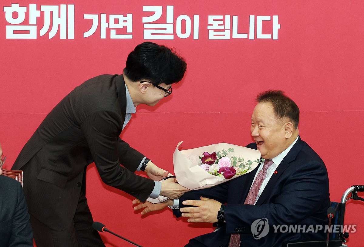 Rep. Lee Sang-min (R) receives a bouquet of flowers from the ruling People Power Party's (PPP) chairman, Han Dong-hoon, at the PPP's emergency committee meeting held in Seoul on Jan. 8, 2024. (Yonhap)