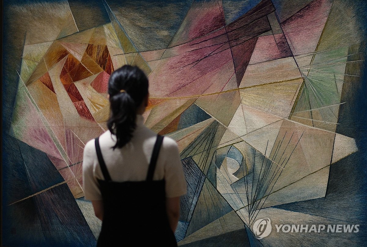 A woman examines an embroidered artwork featured in the exhibition, "Korean Embroidery in Modern Times: The Birds Trying to Catch the Sun," at the Deoksugung branch of the National Museum of Modern and Contemporary Art in Seoul on April 30, 2024. (Yonhap)