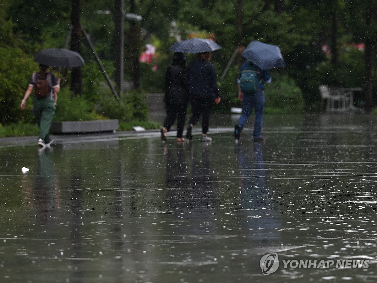 A file photo, taken July 8, 2024, shows people holding umbrellas amid monsoon rain at Gwanghwamun Square in central Seoul. (Yonhap)