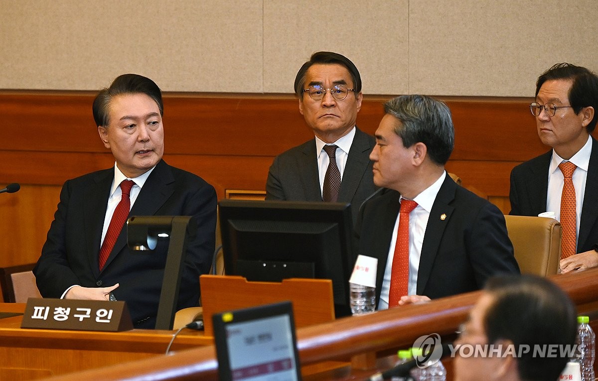 El presidente Yoon Suk Yeol (L) habla con sus abogados mientras asiste a la sexta audiencia de su juicio de juicio político en el Tribunal Constitucional en Seúl el 6 de febrero de 2025, por su imposición de abreviatura de ley marcial en diciembre. (Foto de la piscina) (Yonhap)